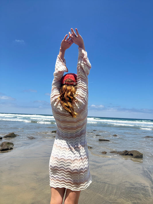 Person in a white dress with a red hat on a beach